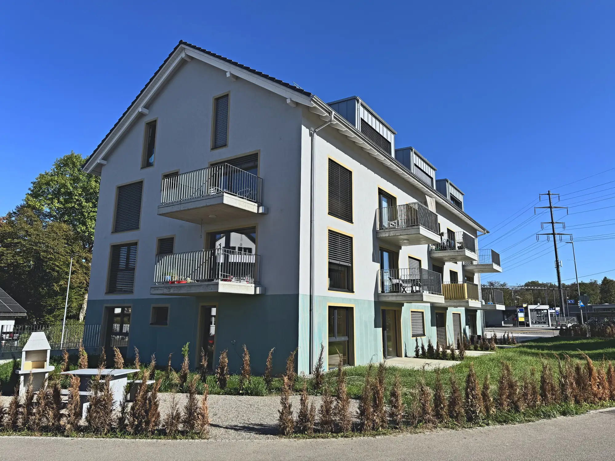 Gartenseite mit Balkonen, Grillplatz und Sitzbank vor der Hecke