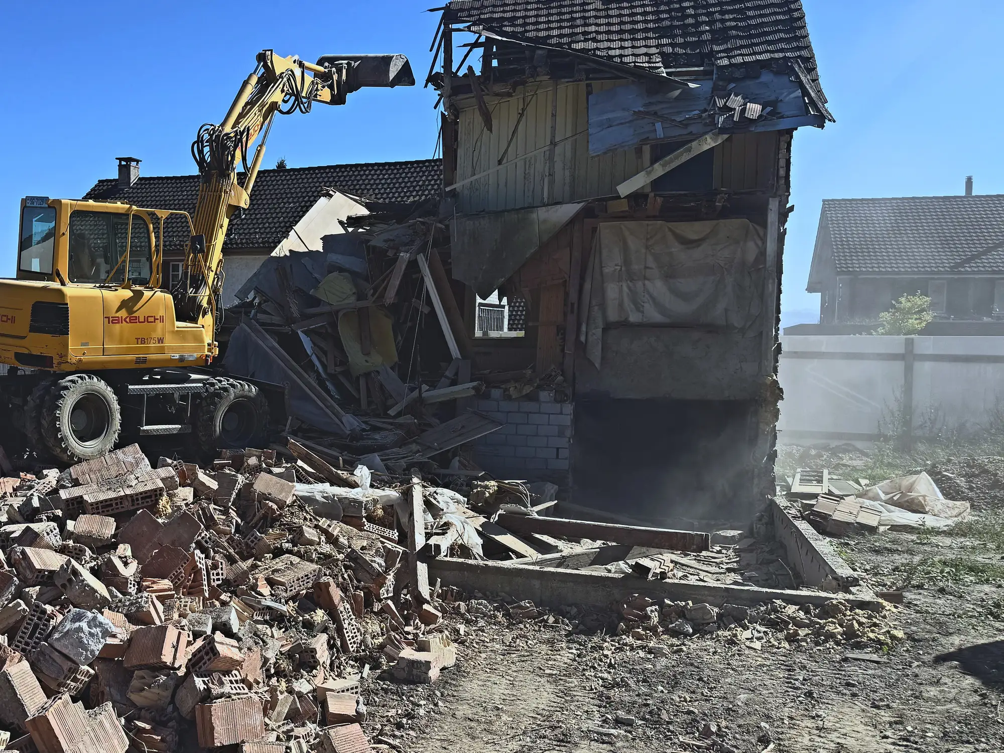 Backsteinschutt vor dem angebrochenen Altbau, Bagger auf dem Trümmerfeld, Romanshorn