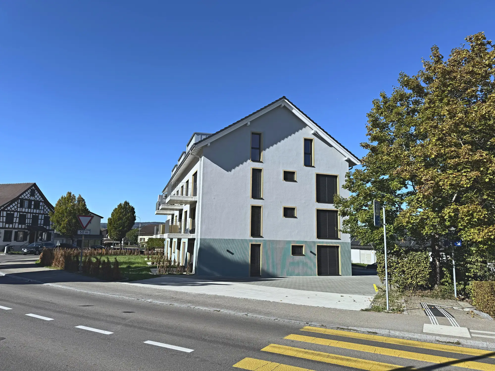 Das Haus an der Dorfstrasse, links ein Riegelbau, rechts die Baumreihe