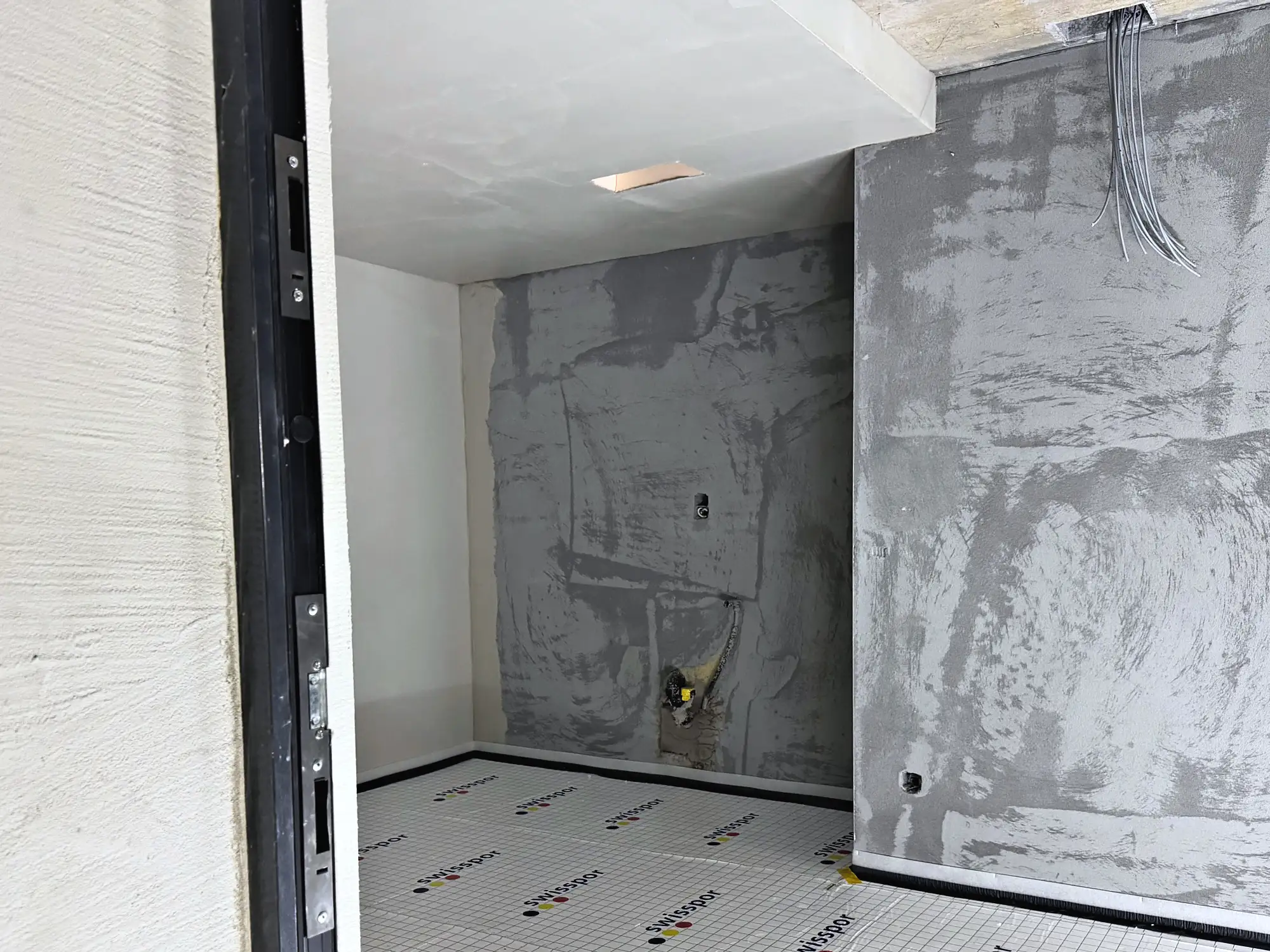 Innenraum mit Betonwand und vorbereitetem Bodenaufbau