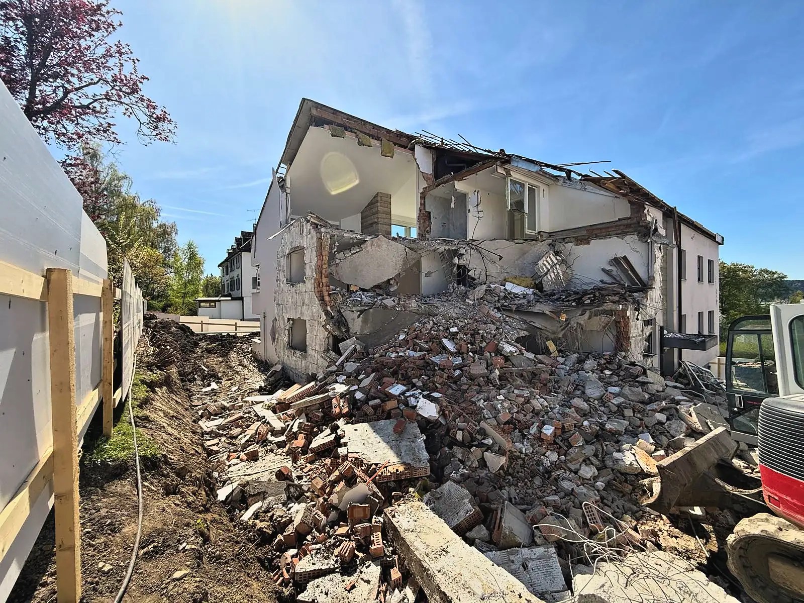 Teilweise abgebrochener Altbau mit acht Wohnungen, Bagger und Bauschutt davor